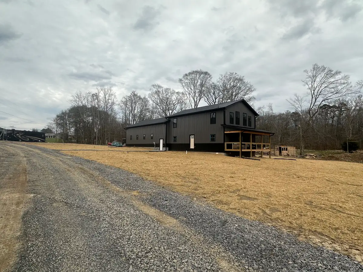 A long gravel driveway curving up to a new home on a cleared and graded lot