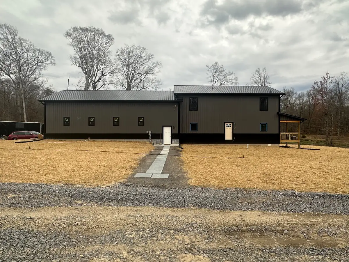 A new dark-sided home with a gravel drive and a stone walk across a freshly graded and strawed yard