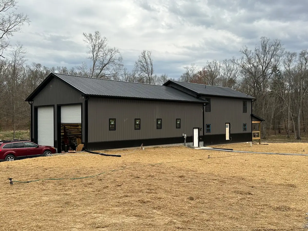 A metal-sided home with two garage doors on a newly graded and seeded lot